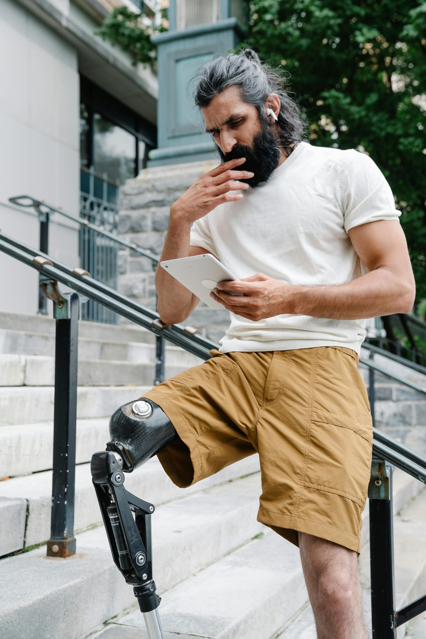 man with artificial leg is standing on stairs and reading from his tablet